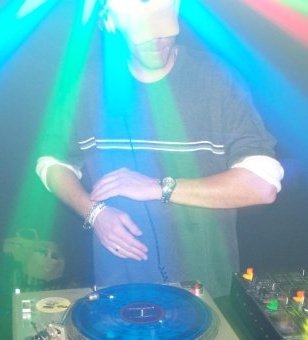 DJ Natural Nate® spinning under colorful stage lighting